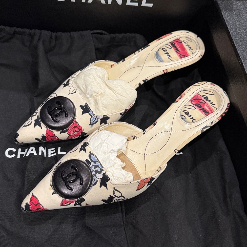 CHANEL Cream Floral Mules with Black Emblem.